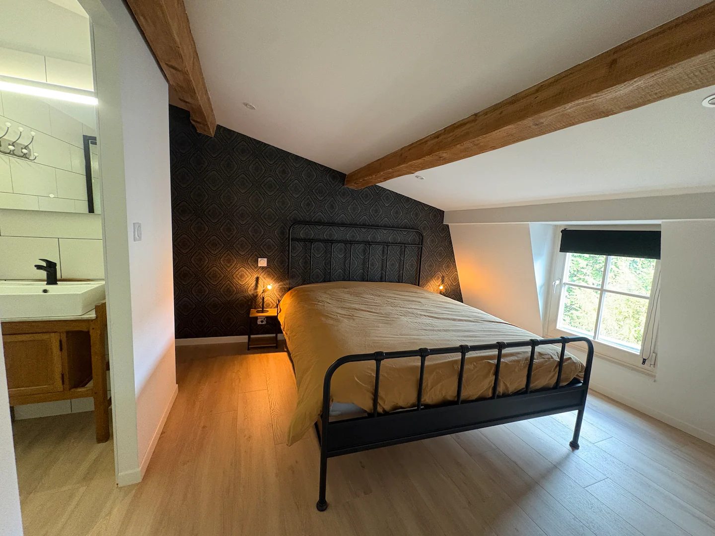 Chambre avec lit en métal noir et salle d’eau privative